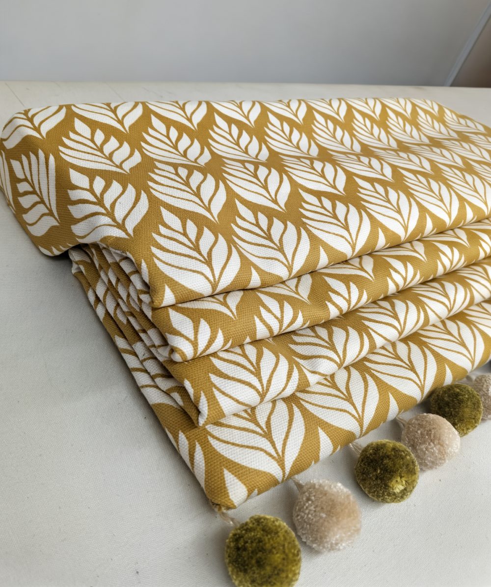 Folded leaf-print fabric alongside pom-pom trim samples