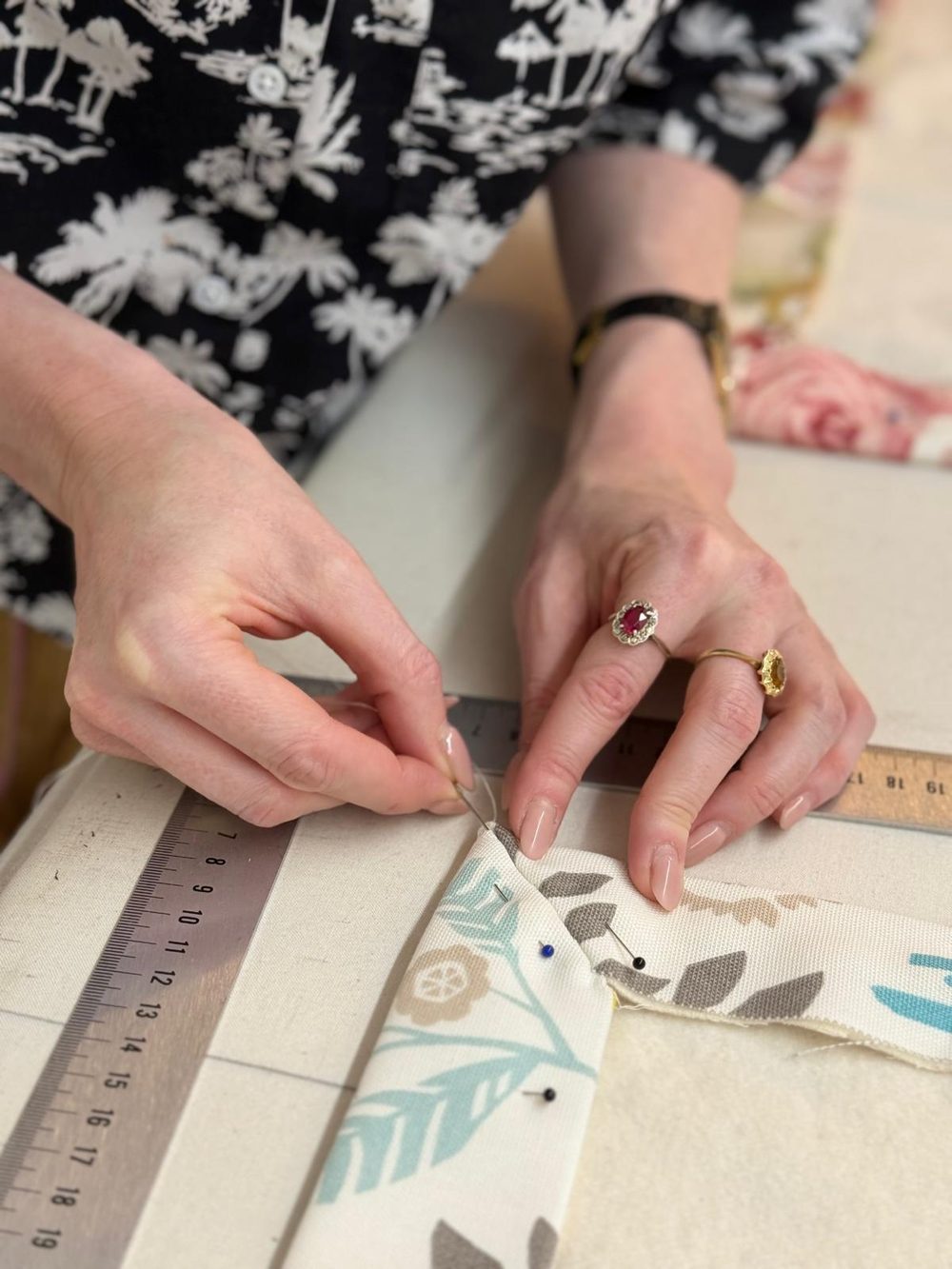 Hands measuring and marking fabric with a steel rule